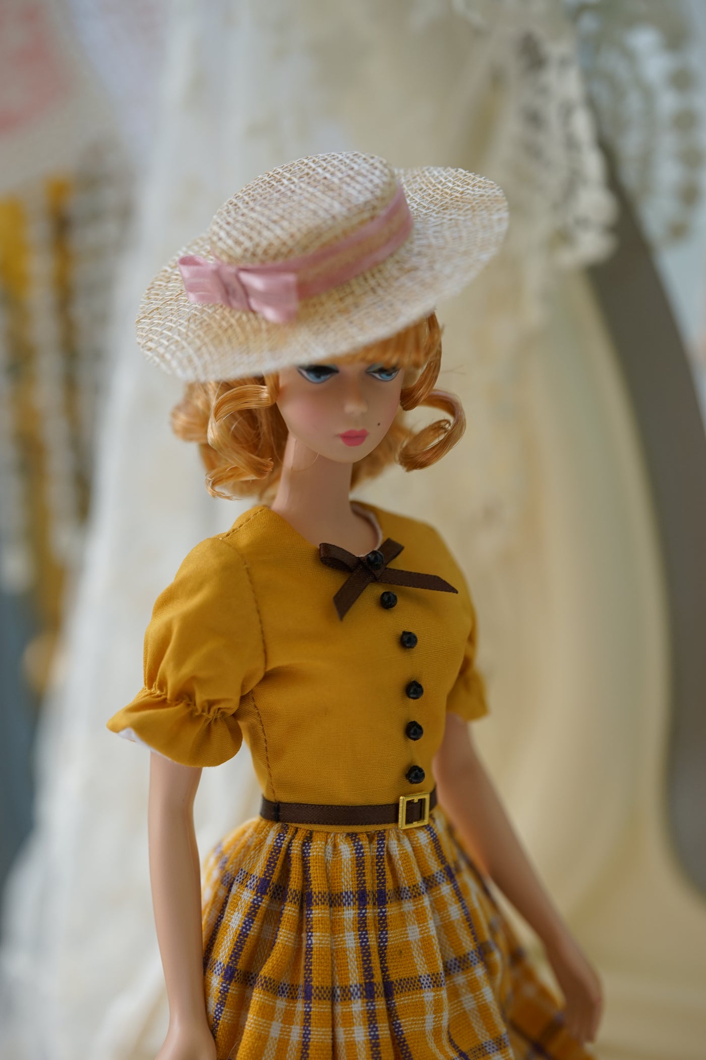 Front view of a beige miniature straw hat with a soft blush pink bow