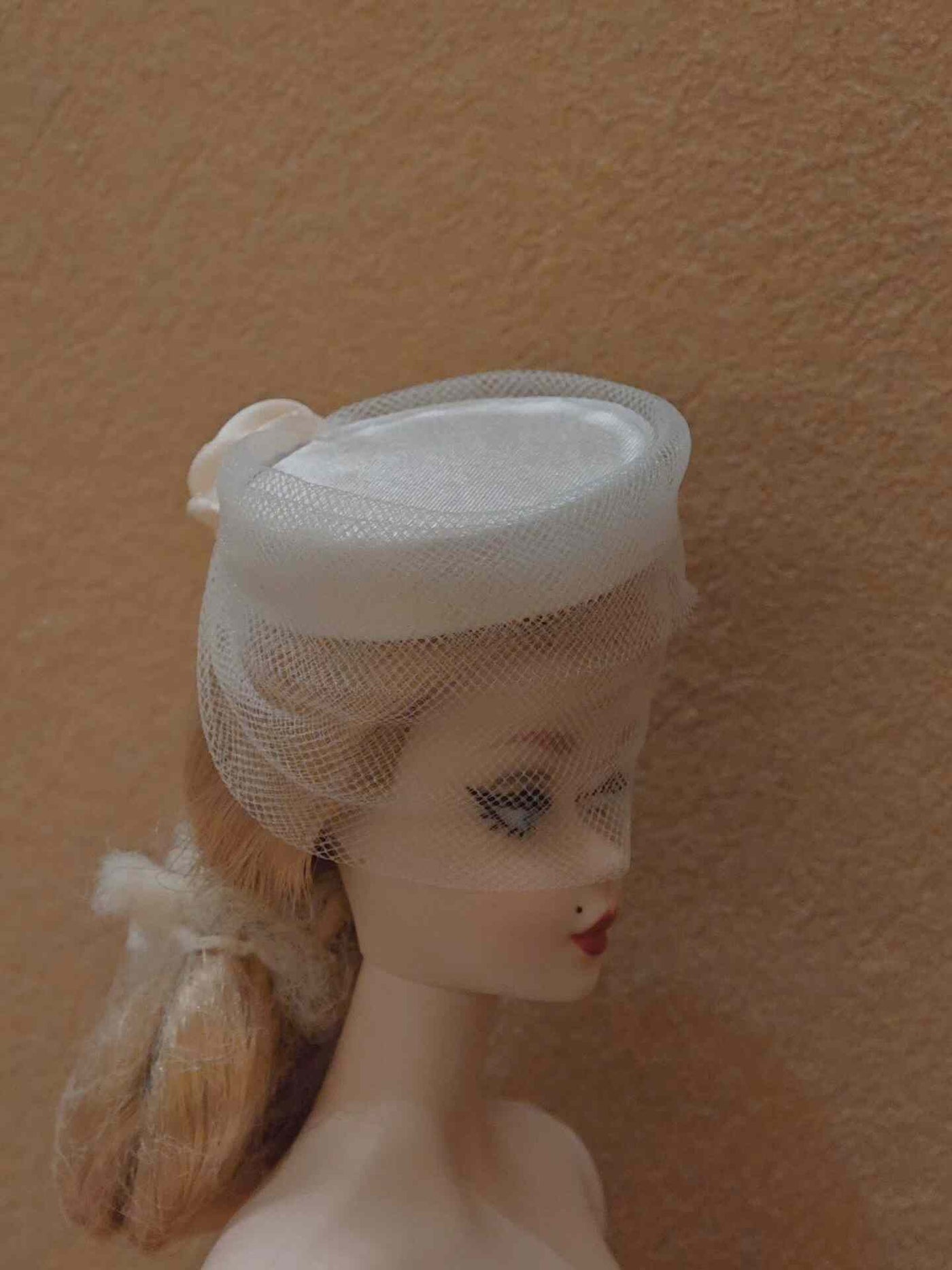 Close-up of the  ribbon and bow on a beige miniature straw hat