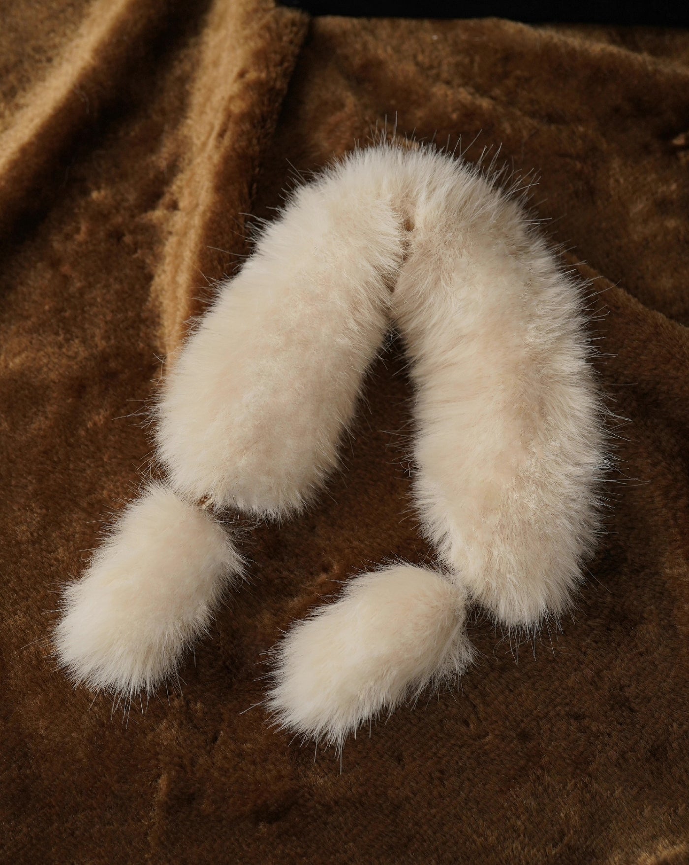 Close-up of beige and black 1/6 scale faux fur stoles with rhinestone clasp detail