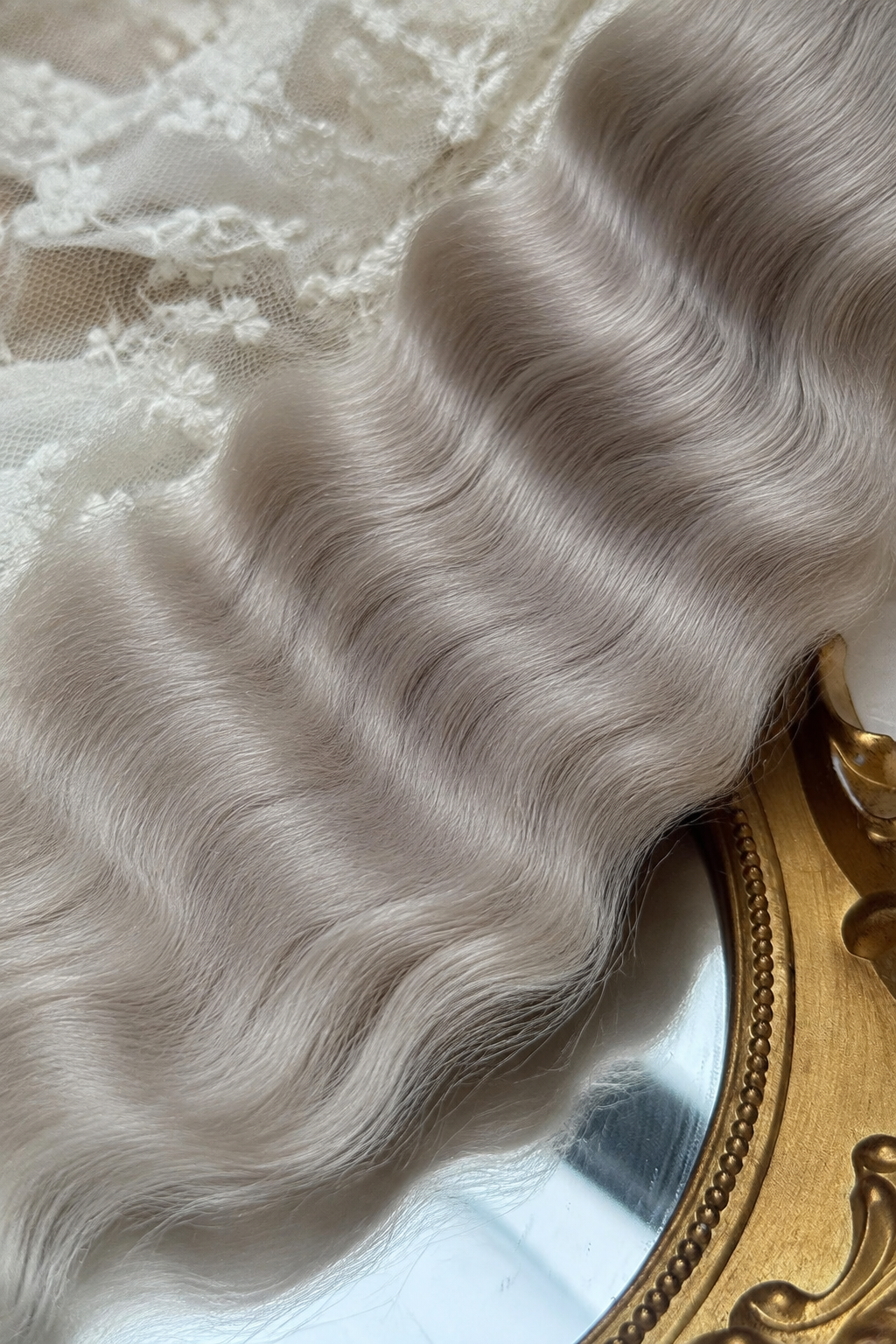 Close-up of ash blonde natural mohair doll hair showing fine fibers, waves and silky sheen