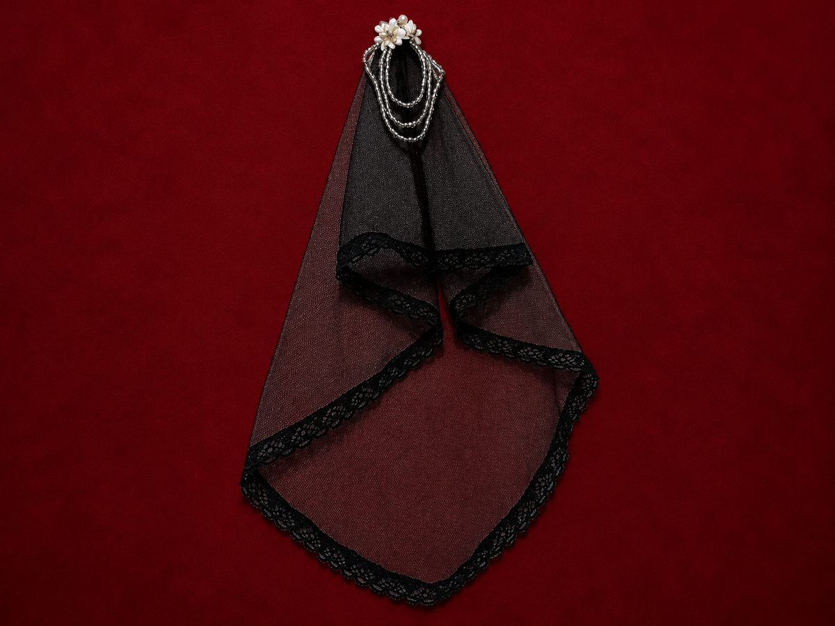 Black lace bridal veil with pearl hair ornament on deep burgundy textured background