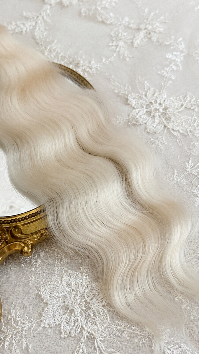 Platinum blonde natural mohair doll hair, three-quarter view on ivory lace with a gold baroque mirror