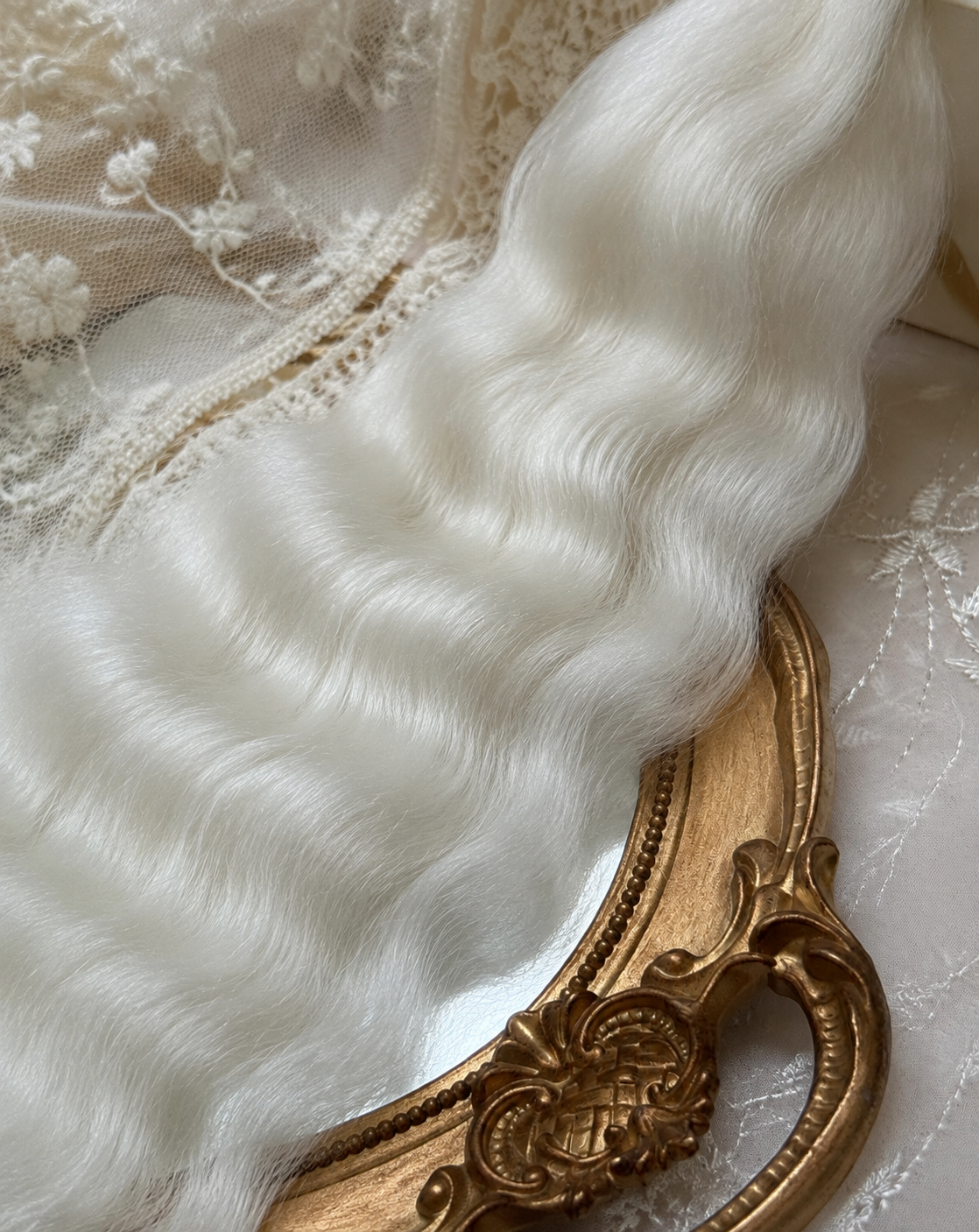 Close-up of white natural mohair doll hair showing fine fibers, waves and silky sheen